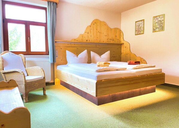 A room with a bed, a chair, a window, and two wall-mounted pictures. - Pension zum Talwächter im Sandsteinidyll (Rathen)
