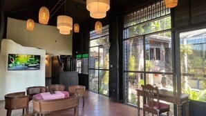 A spacious room with large windows, wicker furniture, and hanging light fixtures. - Sri Ping Resort (Chiang Mai)