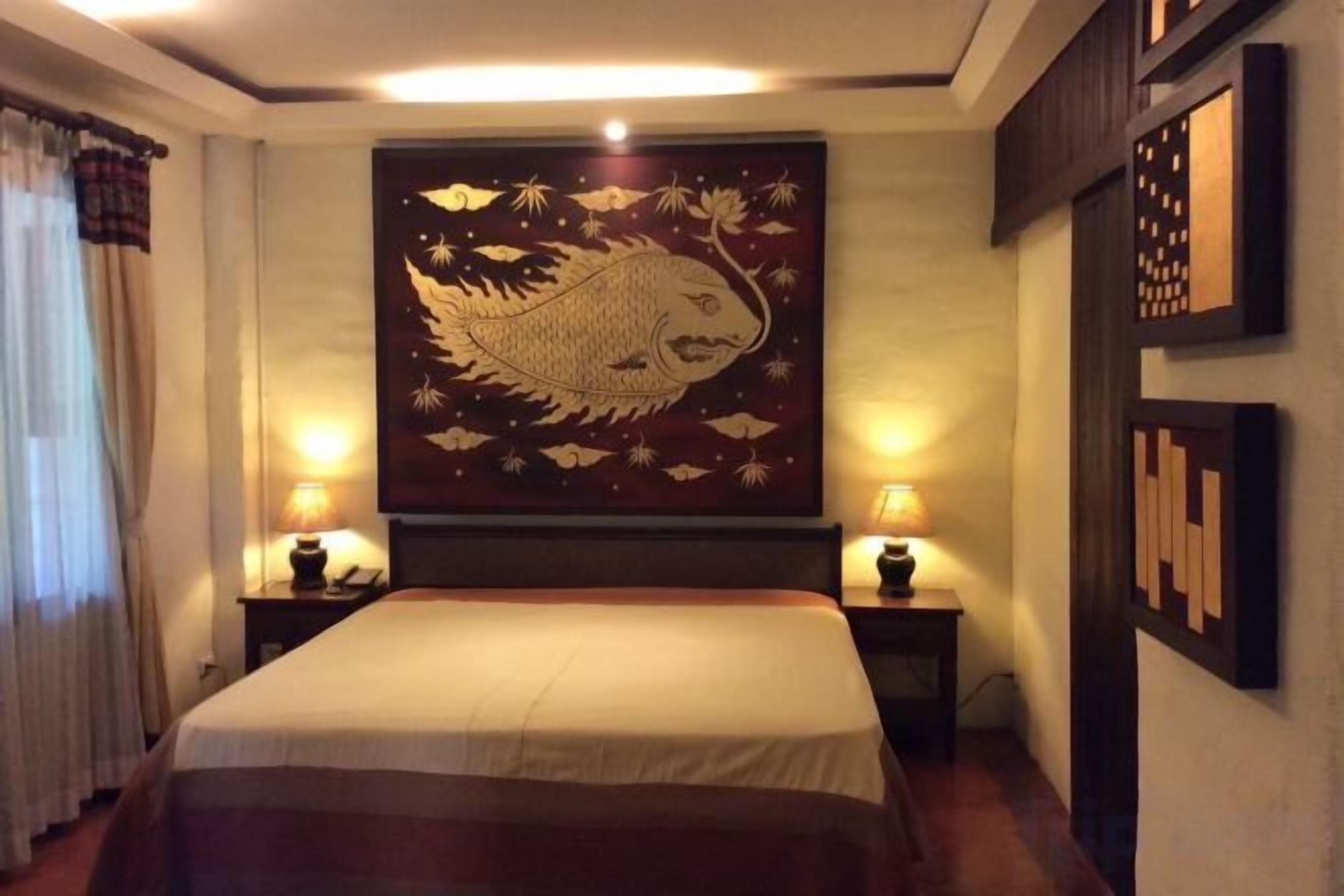 A hotel room with a large bed, two bedside tables with lamps, and a wall with a large fish painting.