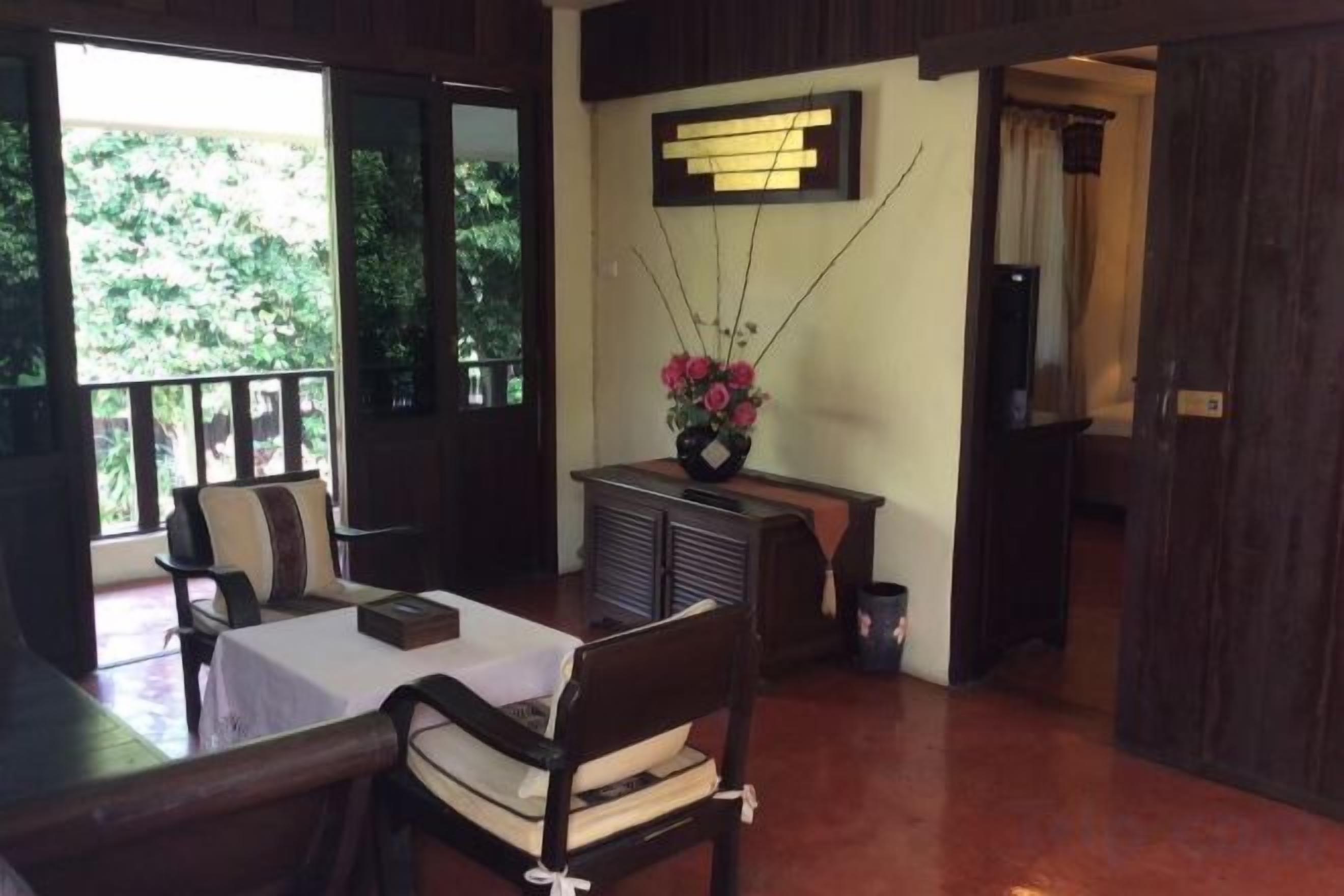 A room with a dining table, chairs, a small cabinet, and a flower vase.
