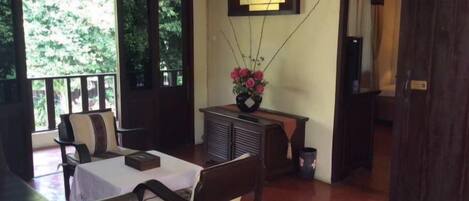 A room with a dining table, chairs, a small cabinet, and a flower vase.
