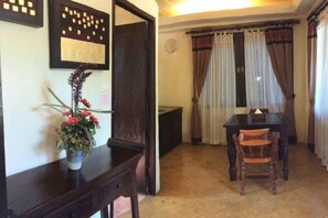 A dining area with a table and chairs, a vase with flowers, and a dark wooden cabinet. - Sri Ping Resort (Chiang Mai)