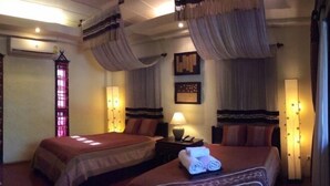 A hotel room with two beds, a window with curtains, a nightstand with a lamp, and wall-mounted lights. - Sri Ping Resort (Chiang Mai)