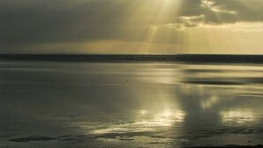 Una playa con un mar tranquilo y un cielo nublado.
