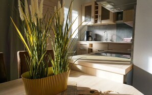 Une cuisine moderne avec un plan de travail en bois, un vase jaune contenant des plantes vertes et une vue sur l’espace cuisine.