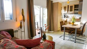Un salon moderne comprenant un canapé, une table à manger et un coin cuisine avec des meubles en bois.