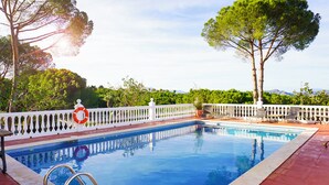 Une piscine entourée d’une clôture blanche, avec une bouée de sauvetage et une pagaie.