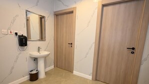 Une salle de bain avec un mur en marbre, un lavabo, un miroir et deux portes en bois.