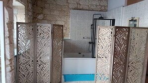 Een badkamer met een bad, douche en decoratieve panelen.