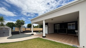 A modern house with a covered patio, a small garden, and a garage. - LaPlaya House 5 minutes from the best beaches! Ideal house for families (Manati)