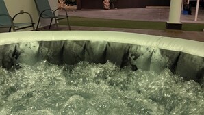A hot tub with water jets, surrounded by lounge chairs and palm trees. - LaPlaya House 5 minutes from the best beaches! Ideal house for families (Manati)