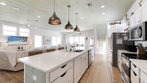 A spacious kitchen with a large island, white cabinetry, and pendant lighting. - No Agenda Hacienda QUARTER MILE WALK TO BEACH (Port Aransas)