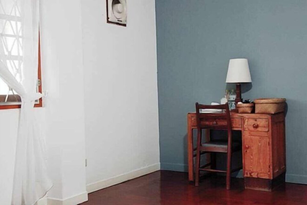 A room with a wooden desk, a chair, a lamp, and a small cabinet.