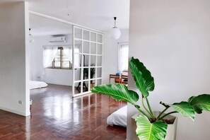 A room with a wooden floor, a sliding glass door, a potted plant, and a bed. - DoubleTree House (Chiang Mai)