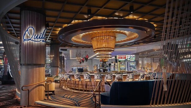 A modern bar area with a circular ceiling design, a bar counter, and patterned seating.