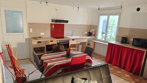 Un espacio habitable compacto con kitchenette, un sofá con cojín estampado y una zona de comedor.