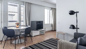 Un salon moderne comprenant un coin repas, un téléviseur à écran plat et une grande fenêtre agrémentée de rideaux.