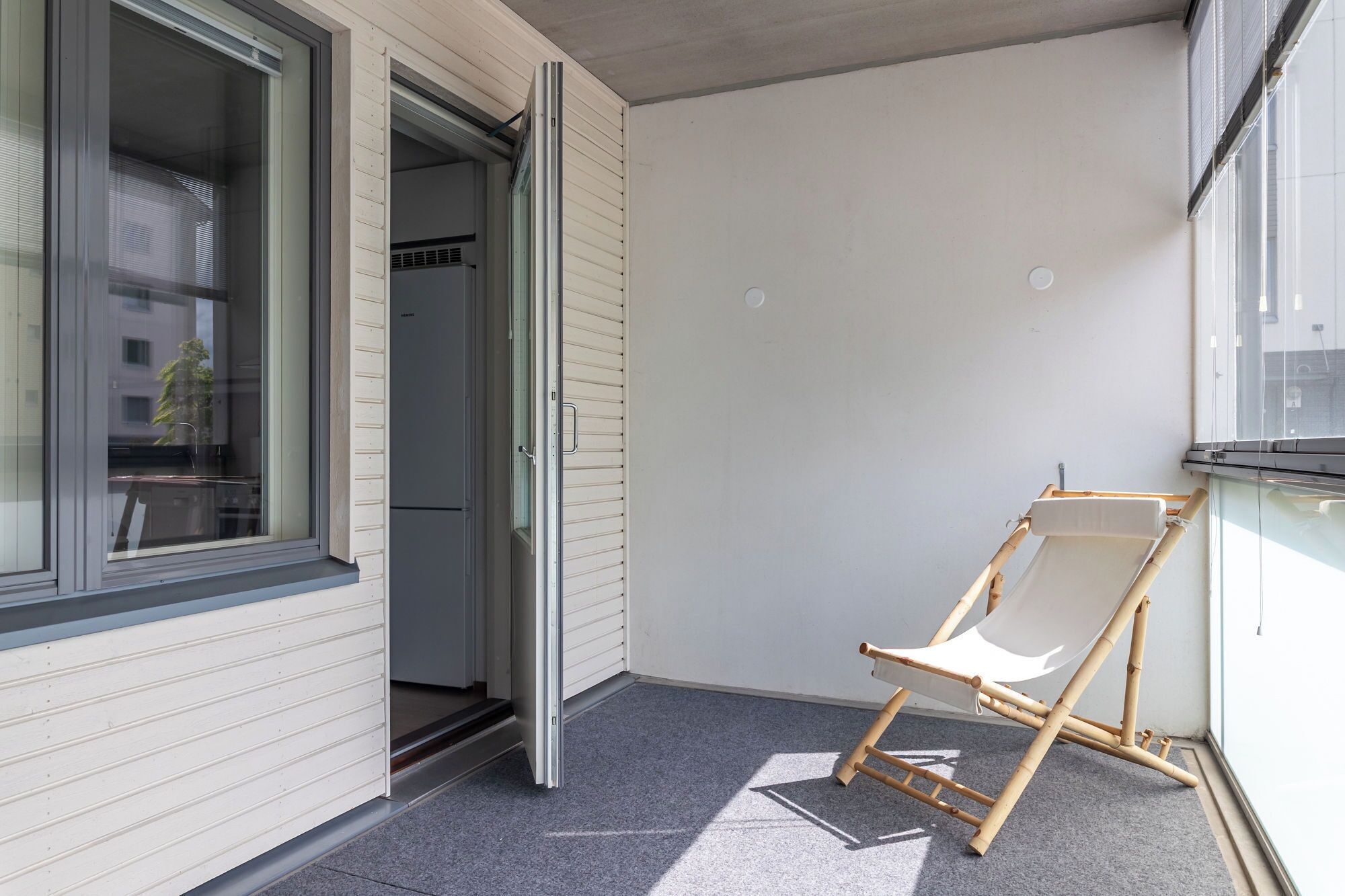 A balcony with a sliding door, a white chair, and a view of a building.
