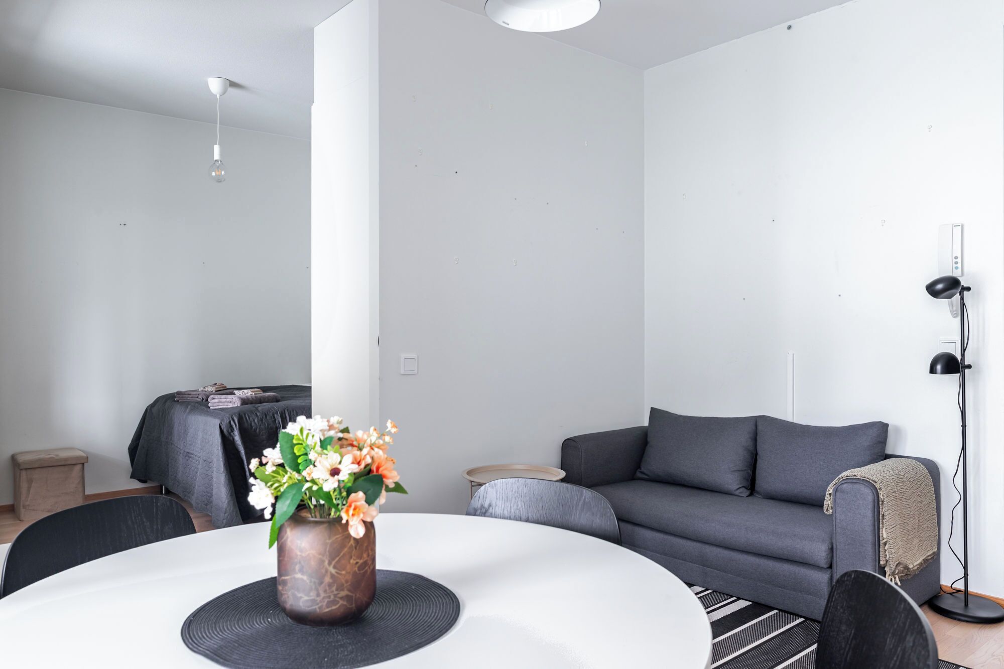 Ein modernes Wohnzimmer mit rundem Tisch, grauem Sofa und einer Stehlampe.