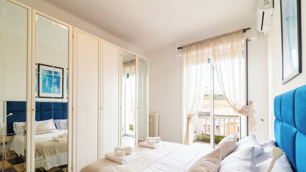 Hotelkamer met een groot bed, een garderobe, een badkamer met spiegel en uitzicht op het omliggende gebied.