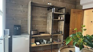 A kitchen with wooden walls, a built-in shelf unit, a coffee machine, and a potted plant. - Villa Oriel Naturiste (Figanières)