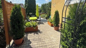 A paved courtyard with potted plants, a wooden fence, and a metal gate. - Vacation apartment (50sqm) with balcony and sun terrace in Frickenhausen (Frickenhausen)