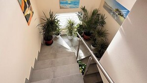 A staircase with potted plants, a painting of a sunset, and a painting of a mountain landscape. - Vacation apartment (50sqm) with balcony and sun terrace in Frickenhausen (Frickenhausen)