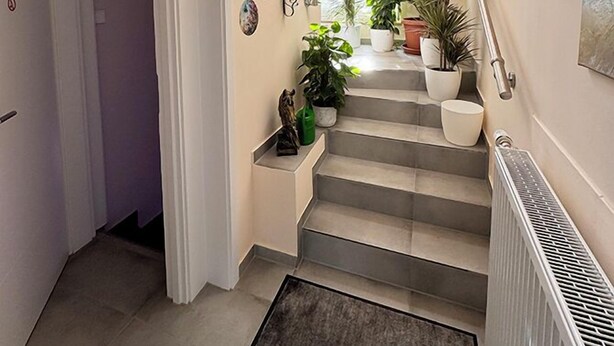 A staircase with potted plants, a radiator, and artwork on the walls. - Vacation apartment (50sqm) with balcony and sun terrace in Frickenhausen (Frickenhausen)