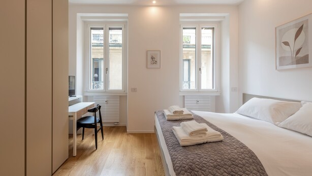 A modern bedroom with a bed, a desk, and a chair. - Milan Royal Suites Duomo (Milan)