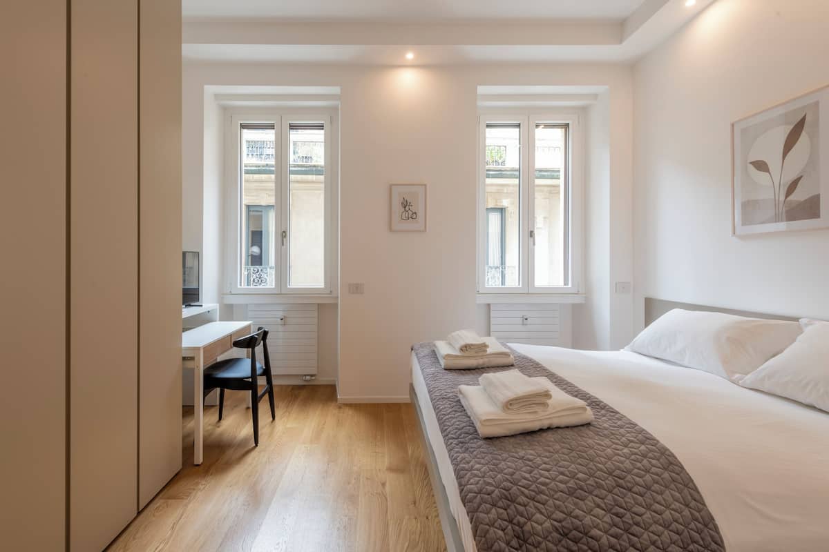 Een moderne slaapkamer met een bed, bureau en stoel.