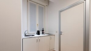 A small kitchenette with a sink, a coffee maker, and a cabinet. - Milan Royal Suites Duomo (Milan)
