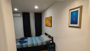 A bedroom with a bed, bedside table, and a wall-mounted picture. - Gisella Surf House (Ladispoli)