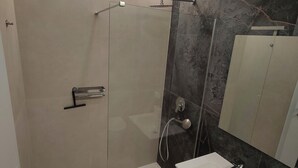 A modern bathroom with a glass-enclosed shower, a white sink, and a dark marble wall. - Gisella Surf House (Ladispoli)