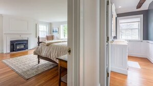 Een ruime slaapkamer met een groot bed, een open haard en uitzicht op de omgeving.