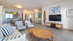 Ein großzügiger Wohnbereich mit Sofa, Sesseln, Fernseher und Couchtisch.