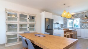 Eine moderne Küche mit einem Holztisch, grauen Stühlen und einer eingebauten Schranke mit Glastüren.