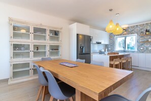 Eine moderne Küche mit einem Holztisch, grauen Stühlen und einer eingebauten Schranke mit Glastüren.