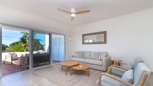 Ein geräumiges Wohnzimmer mit einer Couch, zwei Sesseln, einem Couchtisch und einem Deckenventilator.
