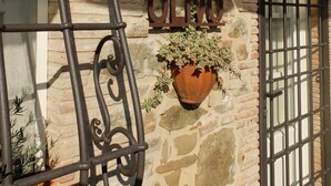 Un muro de piedra con el nombre "OLIVO" y una maceta colgante con plantas.