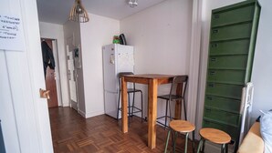 A compact kitchen with a refrigerator, wooden table, and two stools. - Modern accommodation, near Parisian attractions (Paris)
