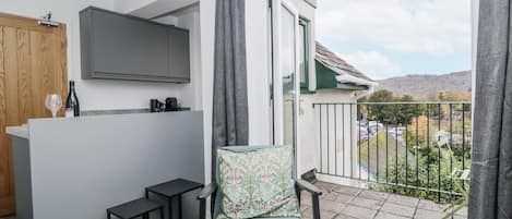 A balcony with a view of a parking area and hills.