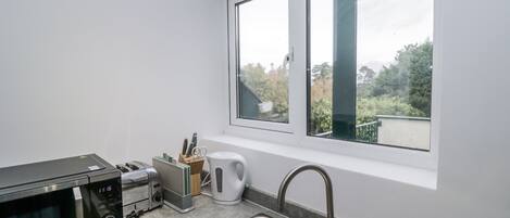 Cucina con microonde, tostapane, lavello e finestra vista sul verde.