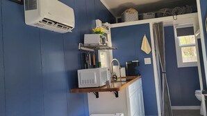 A compact kitchen with a microwave, sink, and white refrigerator.