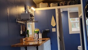 A compact kitchen with a wooden countertop, white appliances, and a blue accent wall.