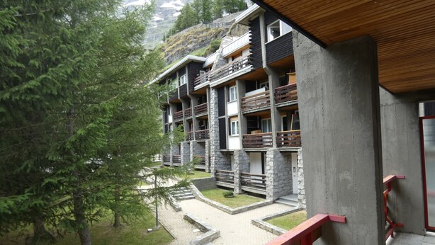 Un edificio de varios pisos con balcones, fachada de piedra y techo de madera.