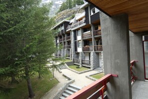 Ein mehrstöckiges Gebäude mit Balkonen, einer Steinaußenwand und einem Holzdach.