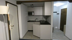 Cocina pequeña con armarios blancos, microondas y pileta.