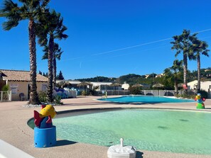 A pool area with palm trees, a clear blue sky, and a sign indicating a first aid station. - Exotic Mobile Home, 40 m² (Fréjus)