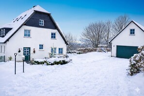 A snow-covered residential area with two houses, a green garage, and a clear sky. - ✨Charming apartment with panoramic views | Eversberg old town in Hochsauerland (Meschede)