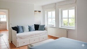 A bedroom with a white sofa, a bed, and two windows with white curtains. - ✨Charming apartment with panoramic views | Eversberg old town in Hochsauerland (Meschede)